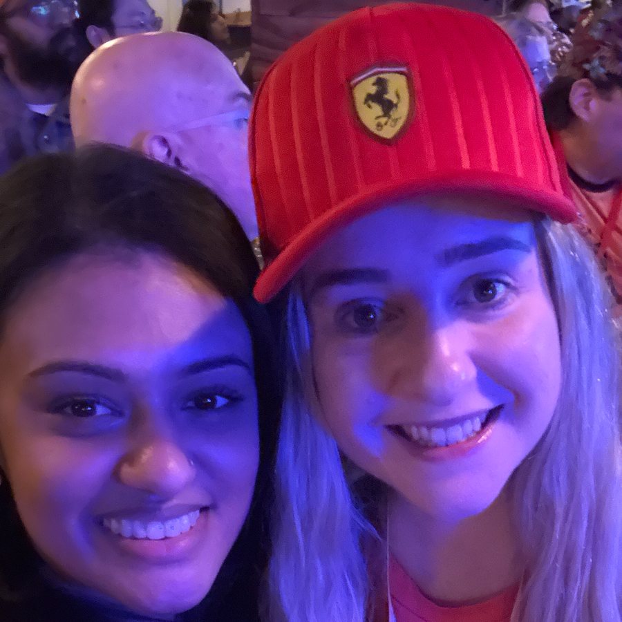 Two friends on race day, one in a red Ferrari cap